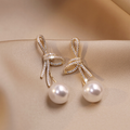 Pearl earrings with a glossy gold bow