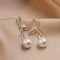 Pearl earrings with a glossy bow in gold
